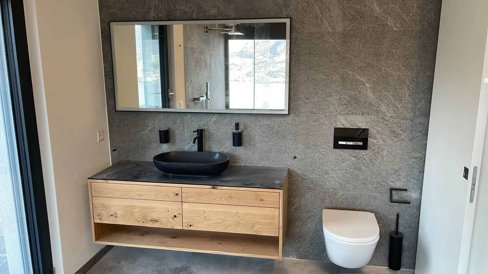 Bagno rifatto con mobile in legno, lavabo nero da appoggio e WC sospeso